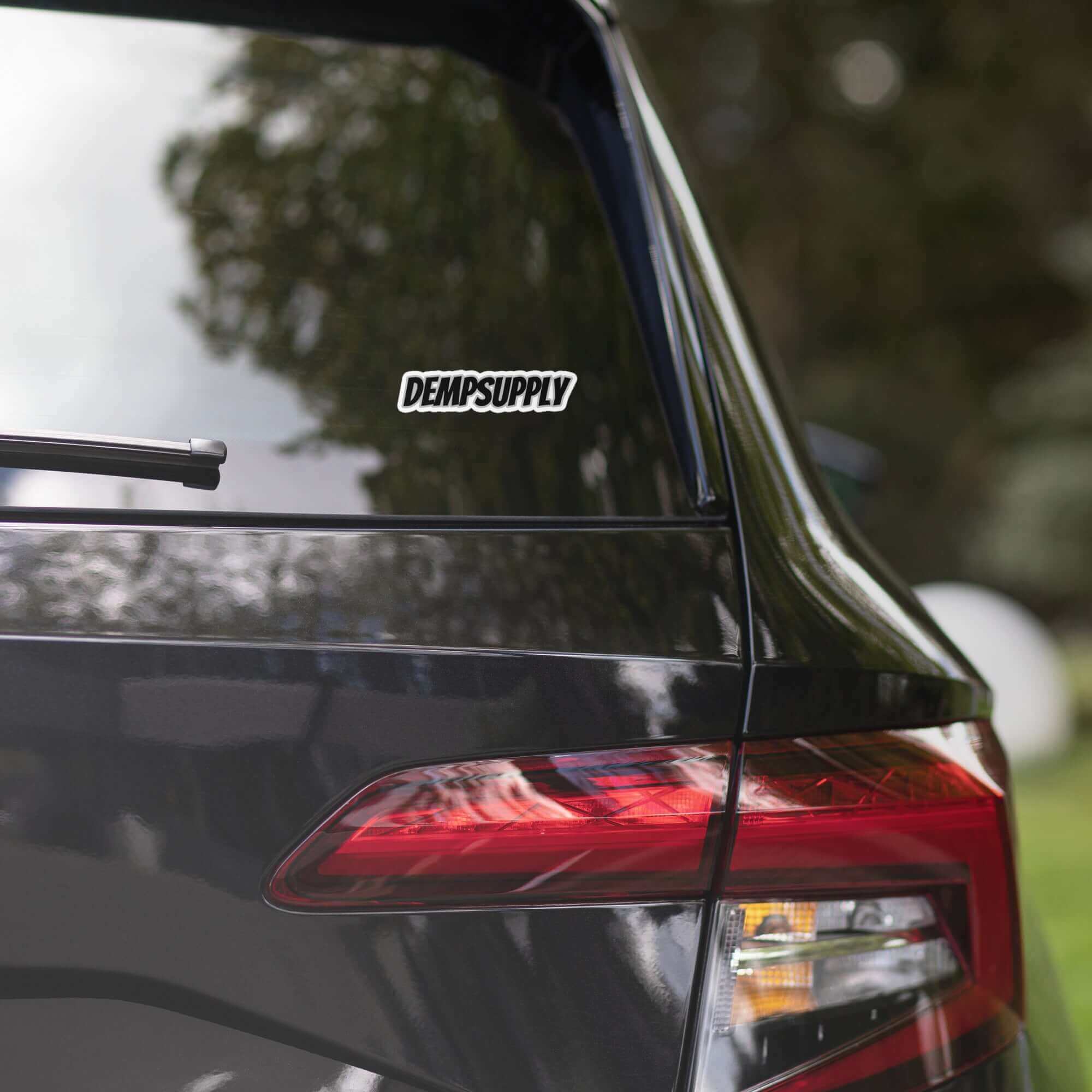 Close-up of a black car's rear window with a DEMPSUPPLY sticker, showcasing automotive personalization.